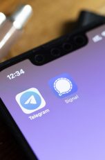 Blick auf ein iPhone, auf dessen Screen die Apps von Telegram und Signal zu sehen sind.