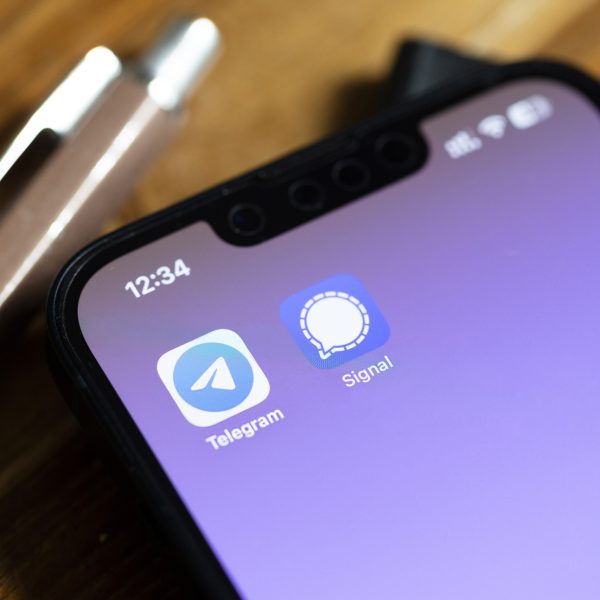 Blick auf ein iPhone, auf dessen Screen die Apps von Telegram und Signal zu sehen sind.