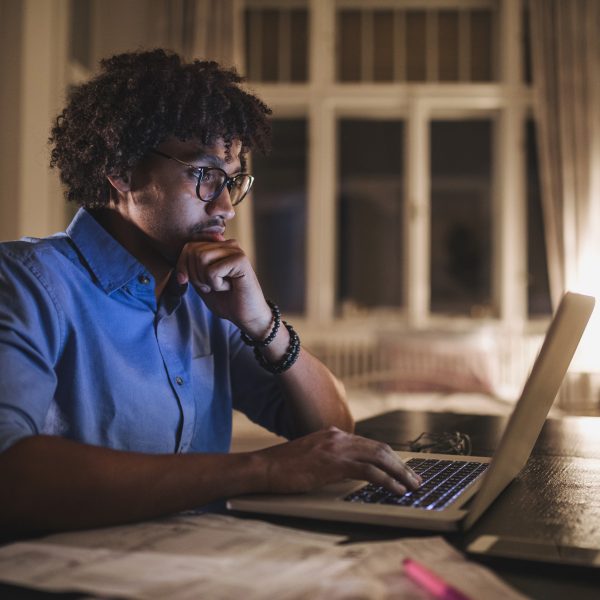 Eine Person sitzt am Schreibtisch vor einem Computer.