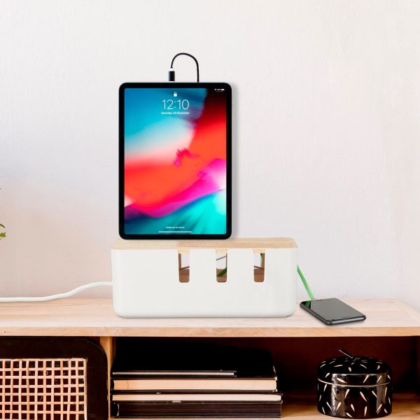 Ein iPad steht auf einer Kabelbox, die wiederum auf einem Schreibtisch aus hellem Holz gestellt wurde.