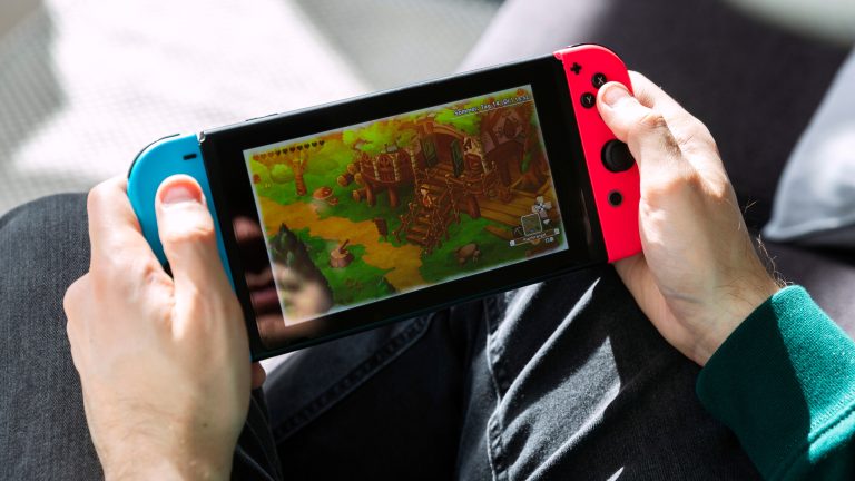 Eine Person hält eine Nintendo Switch in der Hand und spielt ein Spiel darauf.