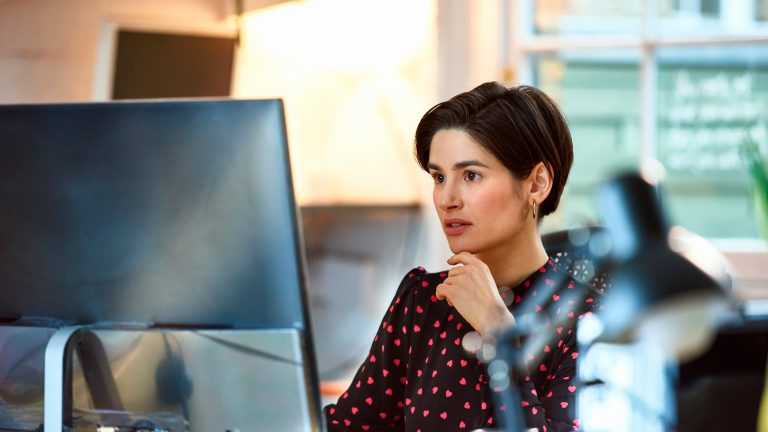 Eine Person sitzt in einem Büro vor einem Computer-Display.