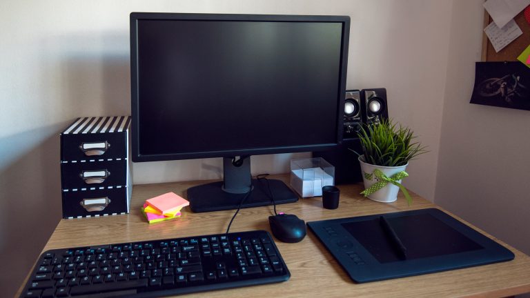 Blick auf einen Schreibtisch mit Bildschirm, Tastatur, Maus und Zeichentablet.