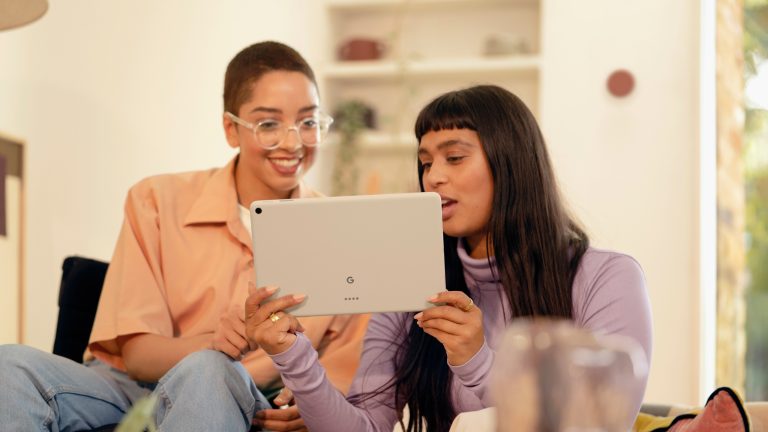 Zwei Personen sitzen auf einem Sofa und schauen gemeinsam auf ein Google Pixel Tablet.