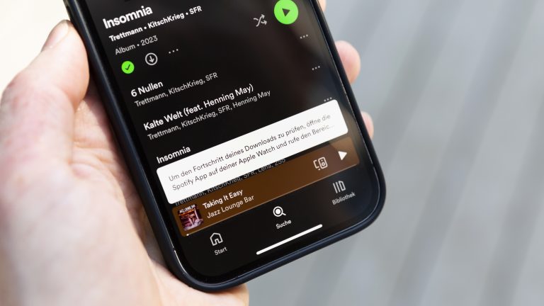 Nahaufnahme eines iPhone 14 Pro, auf dem Spotify einen Hinweis zum Download auf eine Apple Watch anzeigt.