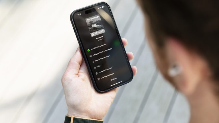 Eine Person blickt auf ihr iPhone, auf dem Spotify geöffnet ist.
