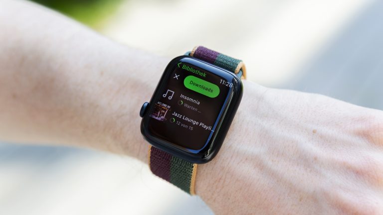 Nahaufnahme einer Apple Watch 8, auf der bei Spotify gerade zwei Downloads laufen.