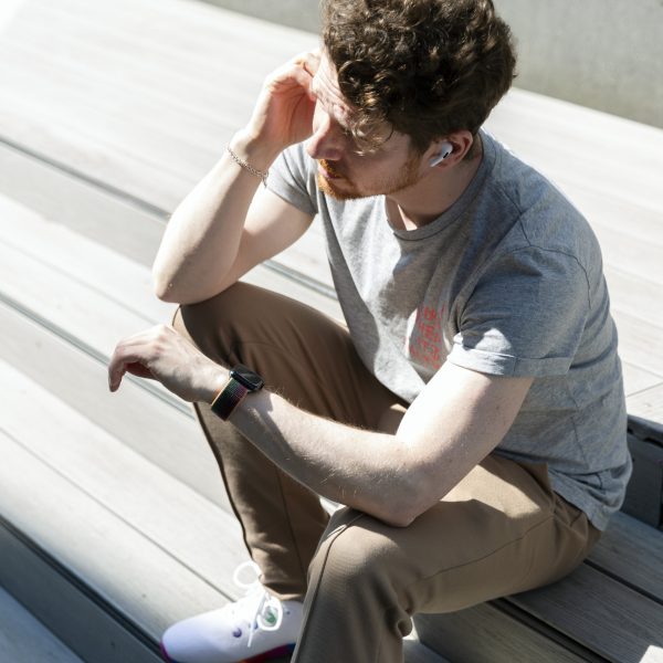 Eine Person sitzt auf einer Treppe und schaut auf ihre Apple Watch. In den Ohren trägt sie Apple AirPods Pro.