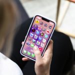 Eine Person h&auml;lt ein iPhone in der Hand, auf dem gerade Apps gel&ouml;scht oder verschoben werden sollen.