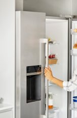 Eine Person steht vor einem geöffneten Kühlschrank.