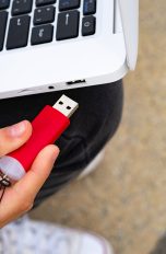 Eine Person ist dabei, einen USB-Stick in einen Laptop zu stecken.