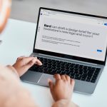 Eine Person sitzt vor einem Laptop. Auf diesem wird Google Bard vorgestellt.