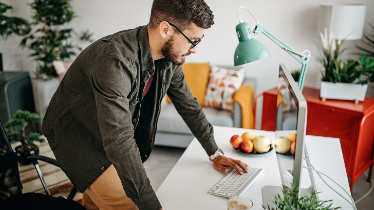 Eine Person stützt die Hände auf einen Schreibtisch, auf dem ein Mac steht.