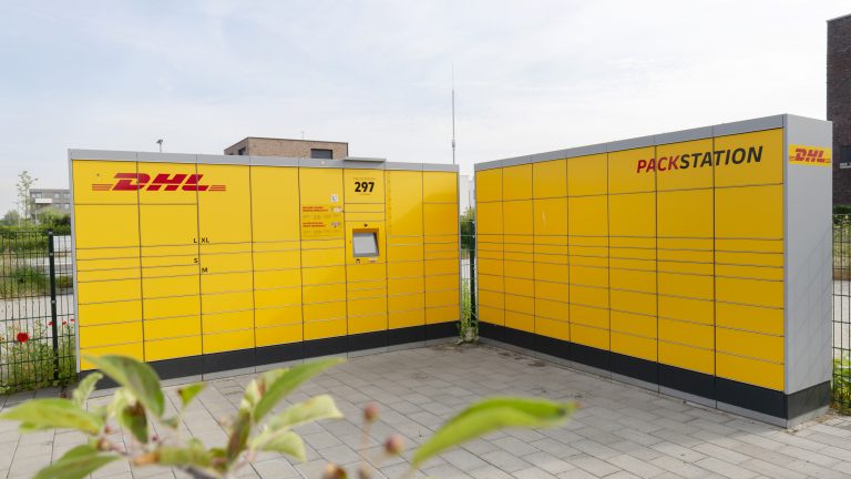 Gelbe Selbstbedienungs-Schließfächer von DHL auf Asphaltboden.