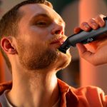 Eine Person rasiert sich mit einem Elektrorasierer im Gesicht.