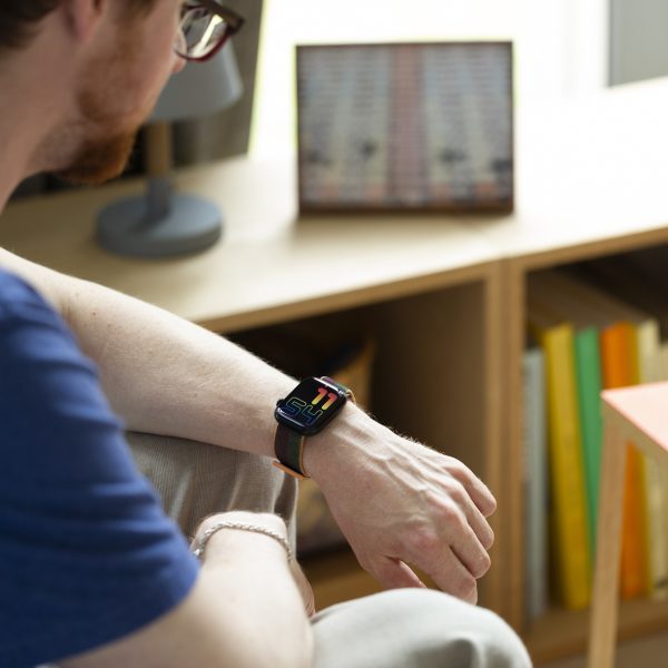 Eine Person sitzt an einem Tisch und schaut auf ihre Apple Watch.