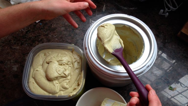 Eine Person entnimmt einem Beh&auml;lter Eis und sch&ouml;pft es in eine verschlie&szlig;bare Plastikschale. 
