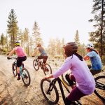 Eine Gruppe von Radfahrer*innen ist auf einem unbefestigten Weg in den Bergen unterwegs.