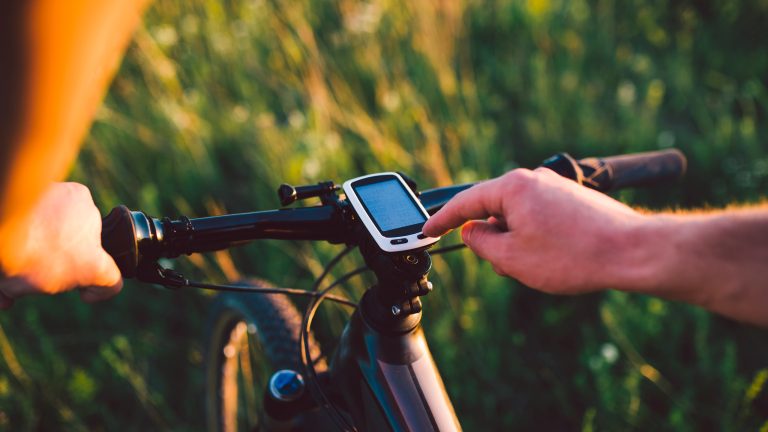 Eine Person bedient einen Fahrradcomputer an einem Mountainbike-Lenker.