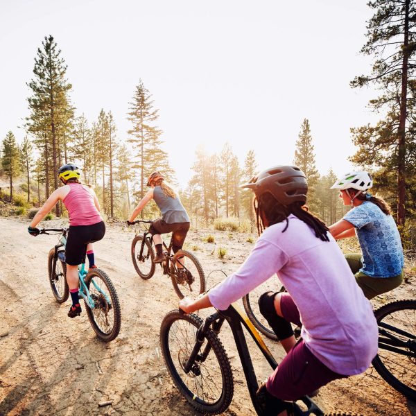 Eine Gruppe von Radfahrer*innen ist auf einem unbefestigten Weg in den Bergen unterwegs.