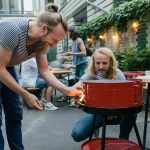 Zwei Personen stehen um einen Grill und entz&uuml;nden diesen.