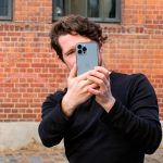 Eine Person h&auml;lt ein iPhone 13 Pro Max Richtung Kamera.