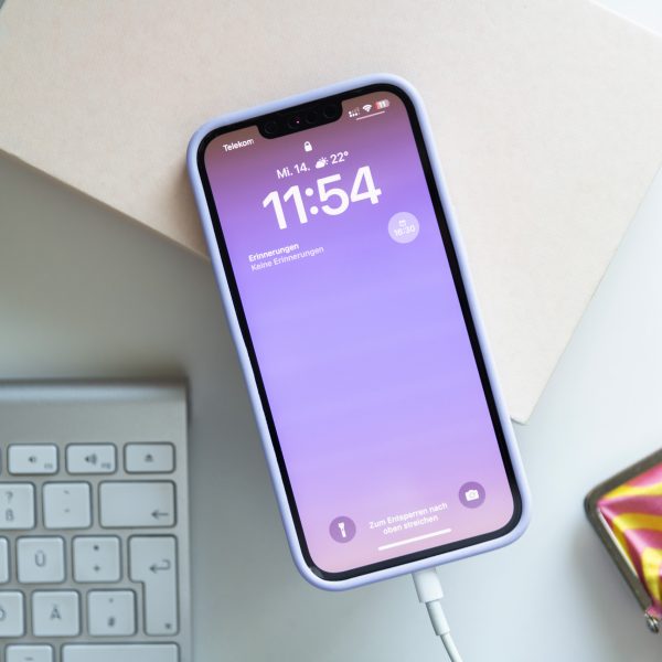 Ein iPhone 13 liegt zwischen mehreren Deko-Elementen und wird &uuml;ber ein Lightning-Kabel aufgeladen.