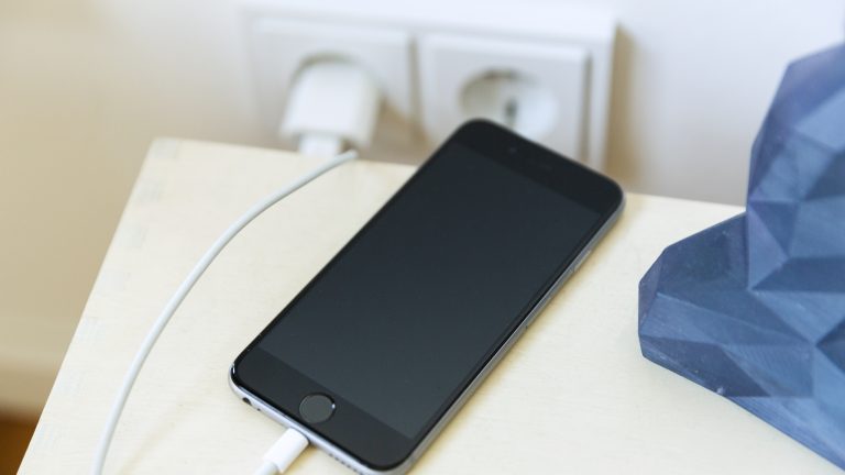 Ein iPhone wird über ein Lightning-Kabel aufgeladen. Der Bildschirm des Geräts zeigt jedoch nichts an.