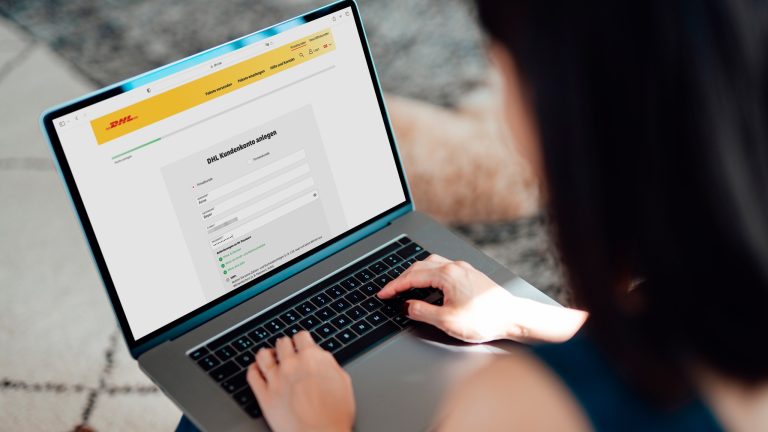 Ein geöffneter Laptop liegt auf dem Schoß einer Person. Auf dem Display ist die Registrierungsseite von DHL zu sehen.