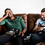 Zwei Personen sitzen auf einem Sofa und halten einige VHS-Kassetten in den H&auml;nden.