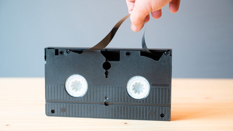 Eine Person zieht ein Magnetband aus einer VHS-Kassette.