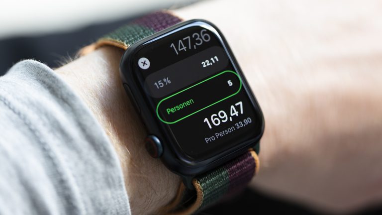 Nahaufnahme einer Apple Watch, auf der mithilfe der Taschenrechner-App ein Rechnungsbetrag samt Trinkgeld kalkuliert wird.