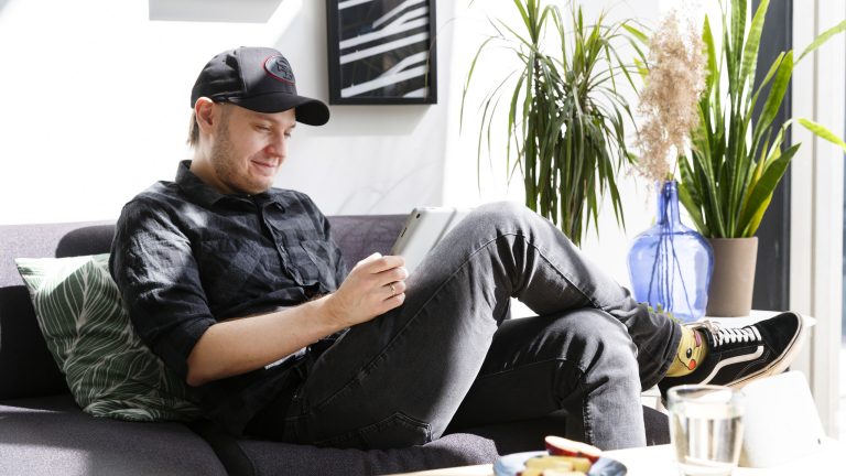 Eine Person sitzt auf einem Sofa und hält ein Google Pixel Tablet in der Hand.