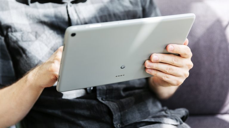 Eine Person hält ein Google Pixel in der Hand. Das Tablet ist von hinten zu sehen.