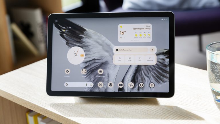 Ein Google Pixel Tablet steht im Dock auf einem Regal. Auf dem Display ist der Homescreen zu sehen.