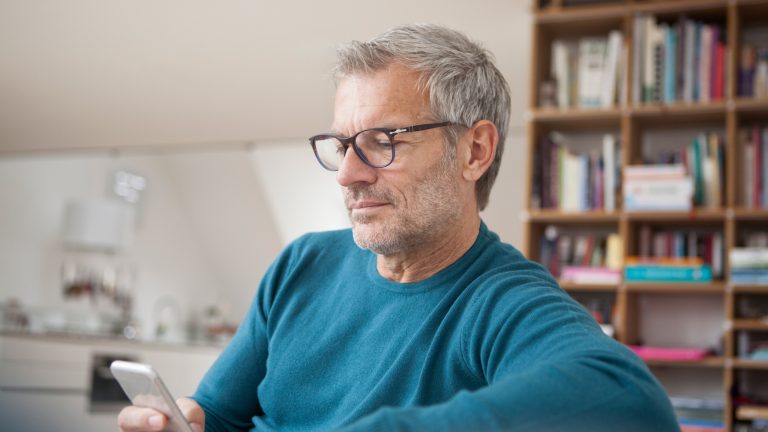 Eine Person sitzt und schaut auf ihr Handy.