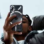 Eine Person h&auml;lt ein Nothing Phone (2) in der Hand, dessen R&uuml;ckseite durch das Glyph Interface illuminiert ist.