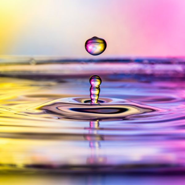 Nahaufnahme eines Wassertropfens, der von einer mit Wasser bedeckten Oberfl&auml;che nach oben prallt.