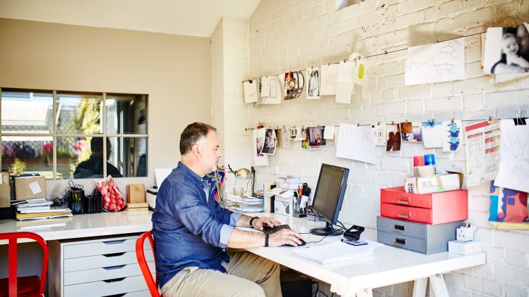 Eine Person sitzt in einem Büro an einem Schreibtisch und tippt auf einer Tastatur.