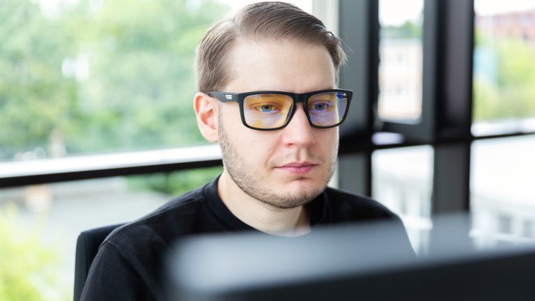 Portraitaufnahme einer Person, die eine Computerbrille trägt.
