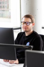 Eine Person sitzt an einem Rechner und trägt eine Computerarbeitsbrille.