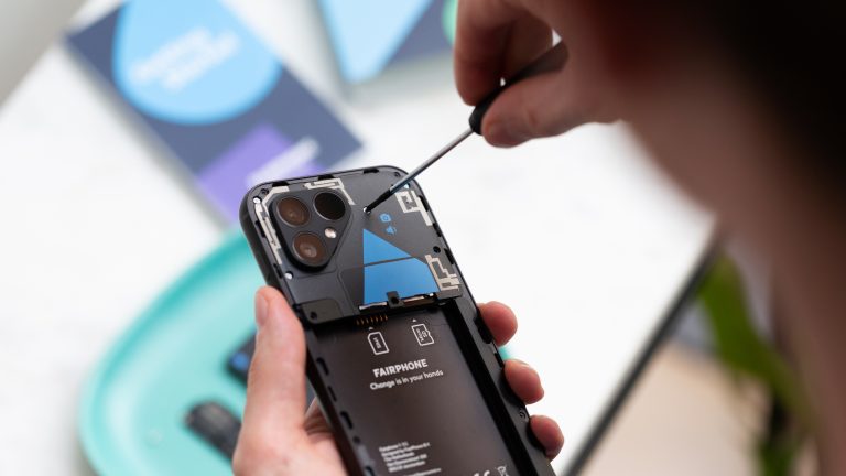 Eine Person schraubt mit einem Schraubendreher die Top-Einheit eines Fairphone 5 ab.