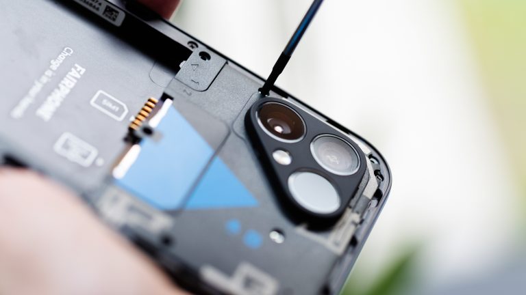 Nahaufnahme eines geöffneten Fairphone 5, bei dem eine Person gerade die Top-Einheit abschraubt.