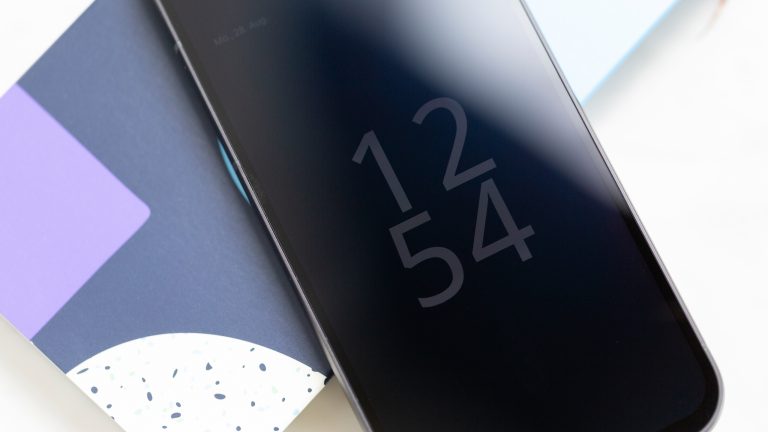 Ein Fairphone 5 mit aktiviertem Always-on-Display liegt auf seinem Karton.