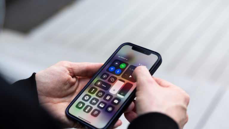 Eine Person tippt auf ein Bedienelement des Kontrollzentrums von iOS.