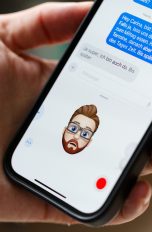 Eine Person hält ein iPhone in der Hand, auf der ein Memoji den Gesichtsausdruck der Person nachahmt.