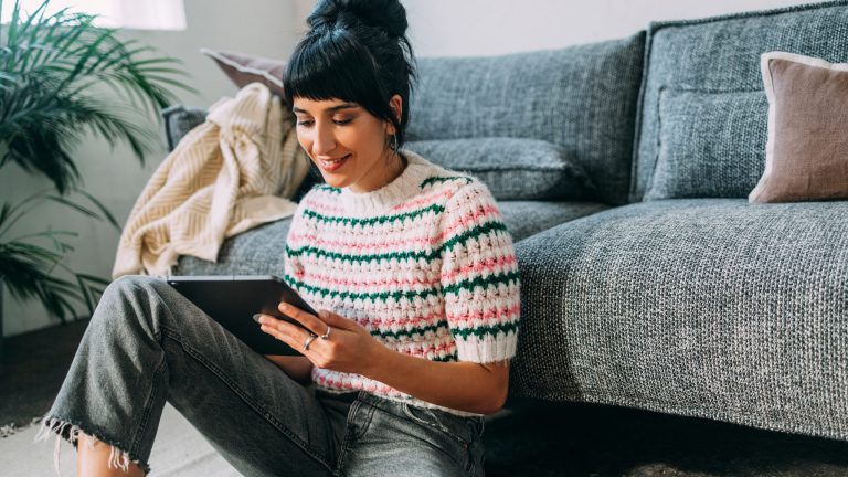 Eine Person sitzt vor einem Sofa auf dem Boden und h&auml;lt ein iPhone in der Hand.