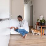 Eine Person hockt vor einem ge&ouml;ffneten Gefrierschrank.