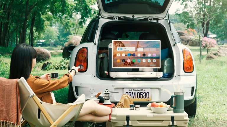 Zwei Personen sitzen vor dem Kofferaum eines Autos. Darin ist der portable Fernseher StandbyMe Go von LG zu sehen.