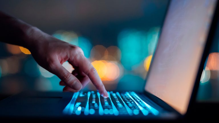 Eine Person tippt auf eine Taste auf einer Laptop-Tastatur. Eine Person tippt auf eine Taste auf einer Laptop-Tastatur.